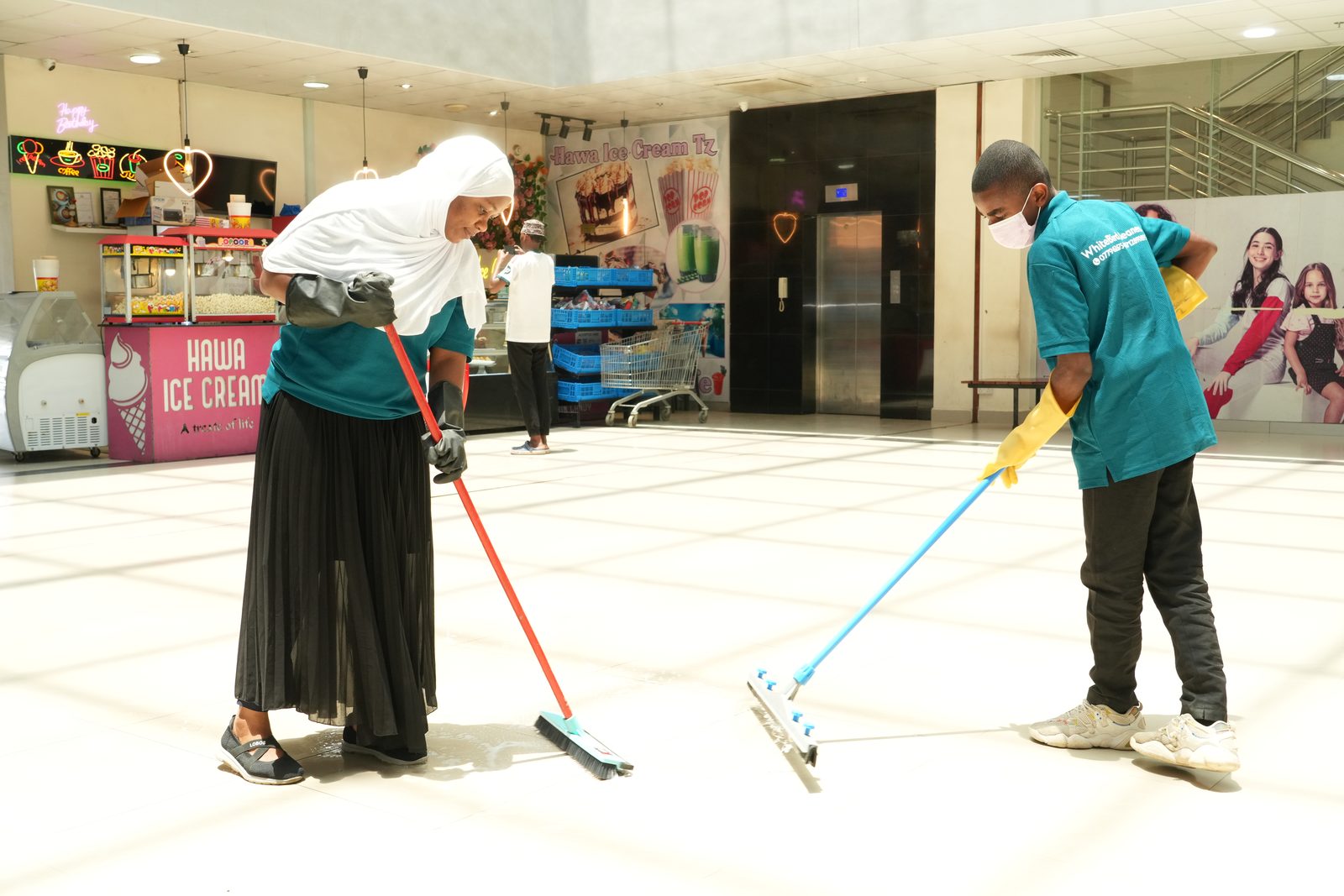 Two WhiteBird cleaners mopping a bright tiled hall during a service visit